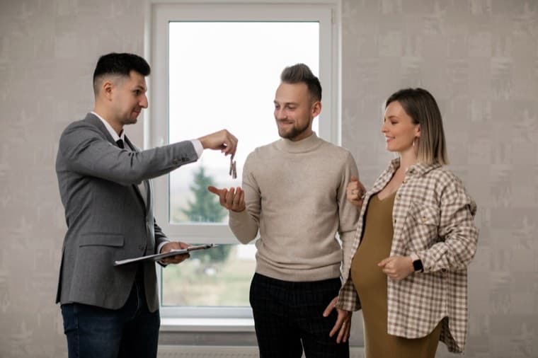 Agente inmobiliario entregando las llaves a nuevos propietarios